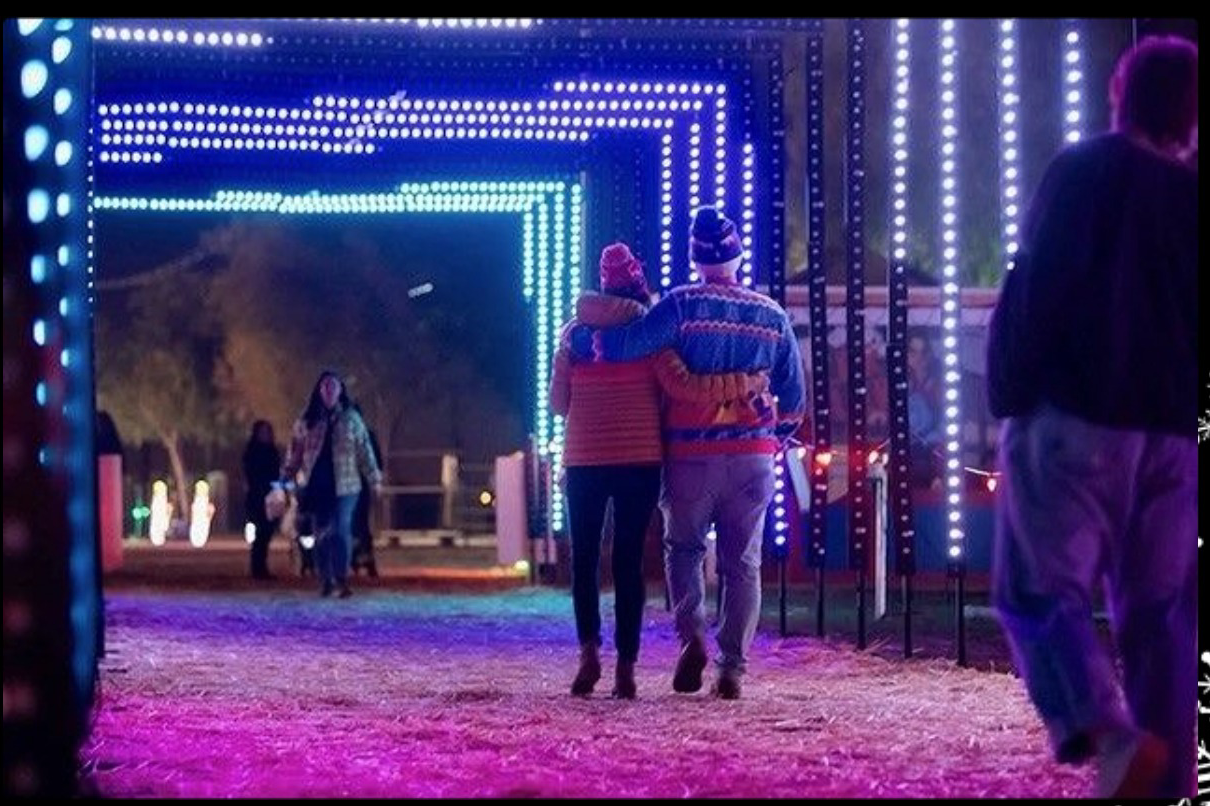 A couple walking the light tunnel at Arizona Christmas Lights in Gilbert