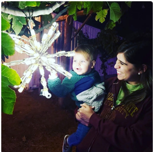 A mother and toddler beside a lit snowflake