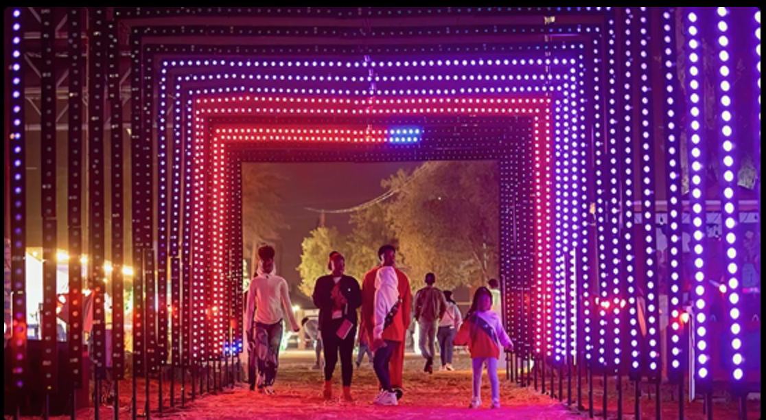 Visitors walking through a lit tunnel at the Gilbert Christmas light show